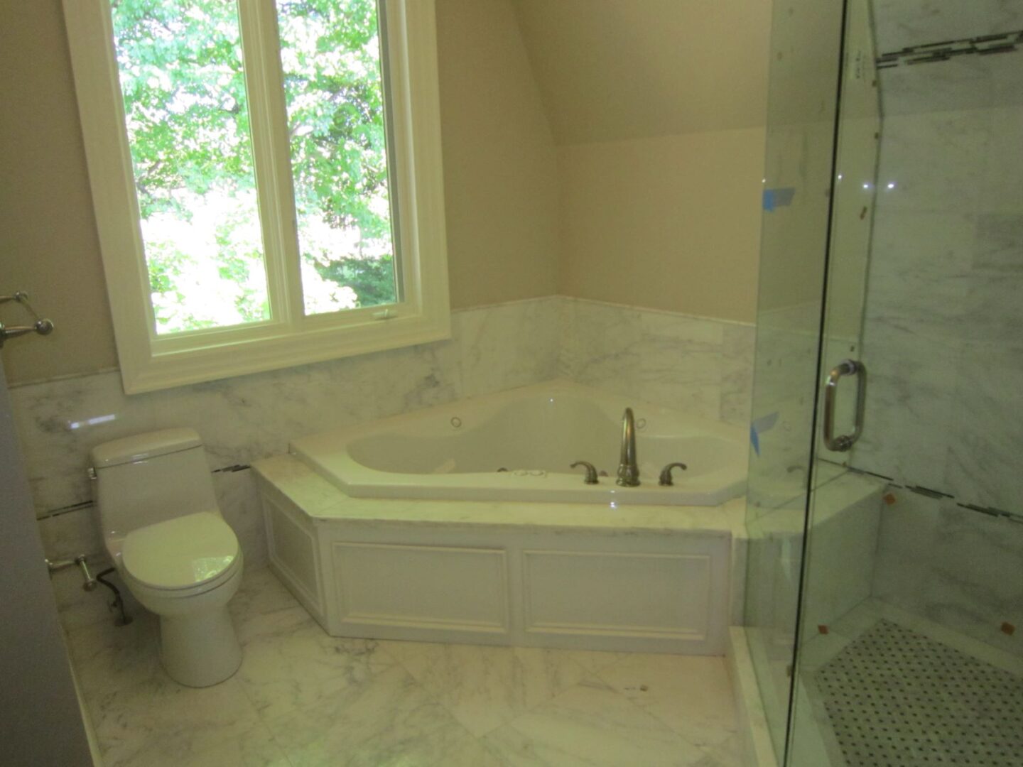 A Corner Bath Tub With Glass Doors Shower