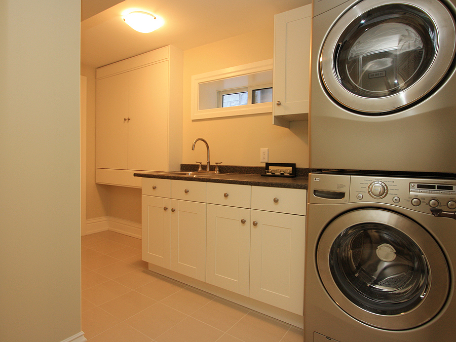 A Laundry Room With White Counter and Brass Knobs